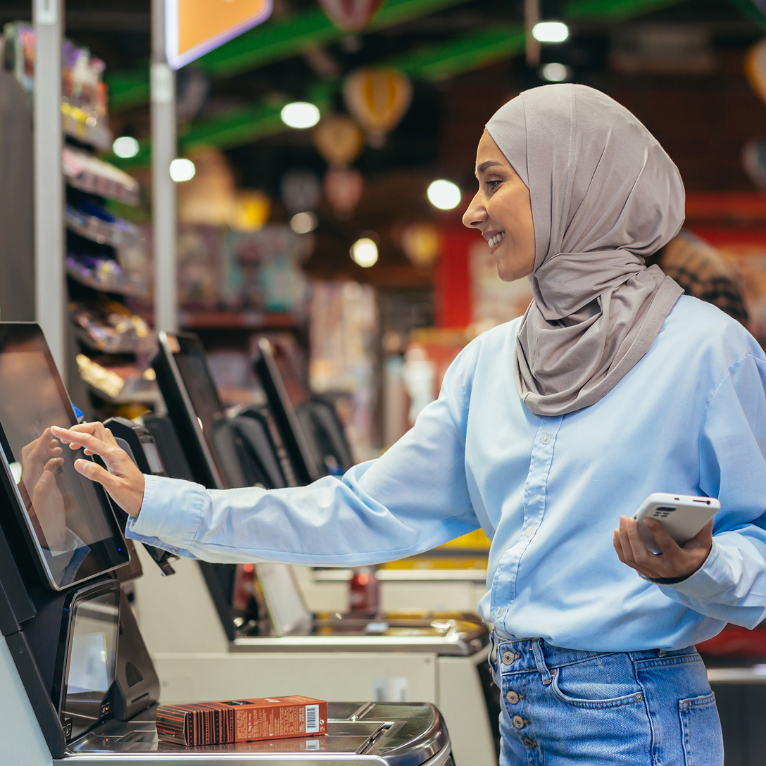 A woman using the self-checkout counter at a grocery store